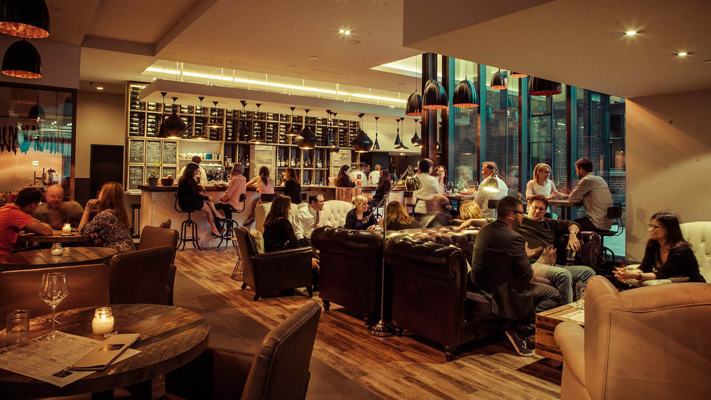 Interior of restaurant warmly lit and groups of people having fun and eating.